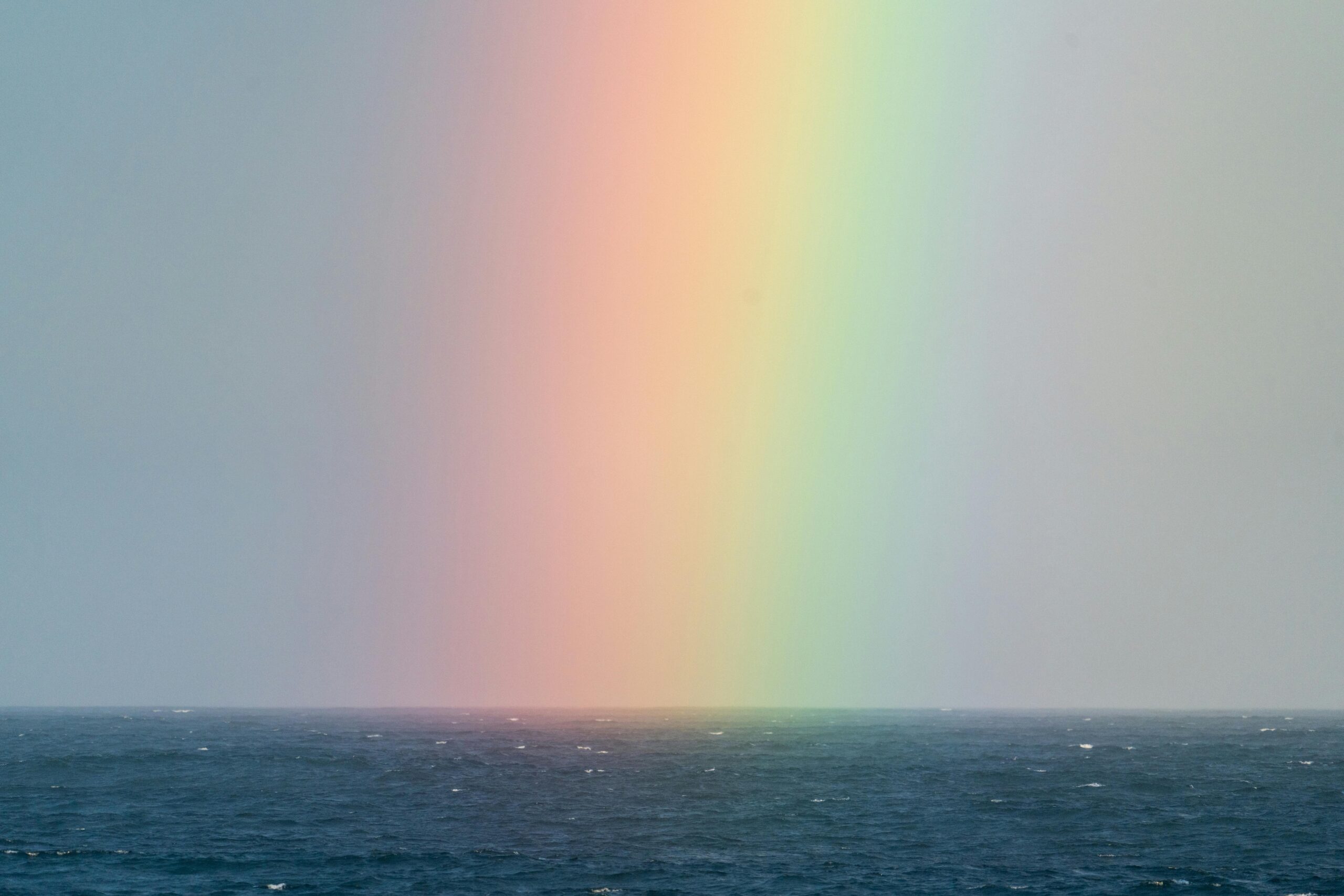 Stunning view of a colorful rainbow stretching over the tranquil ocean horizon.